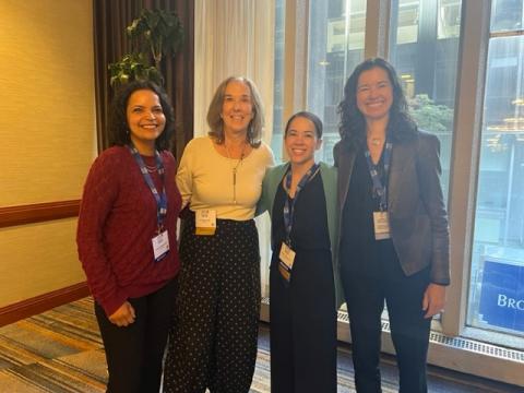 Four women in professional attire standing for a photo at a conference