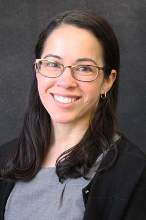 Jennifer McLaren is a woman with shoulder length dark hair and glasses wearing a grey blouse and black sweater